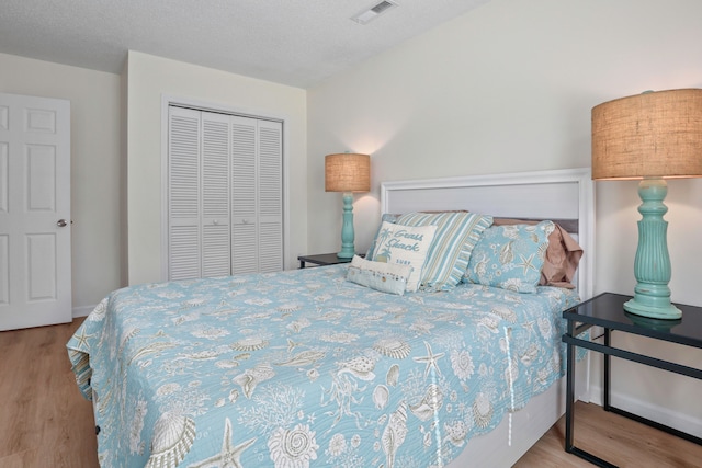 bedroom featuring a closet, a textured ceiling, and light hardwood / wood-style floors