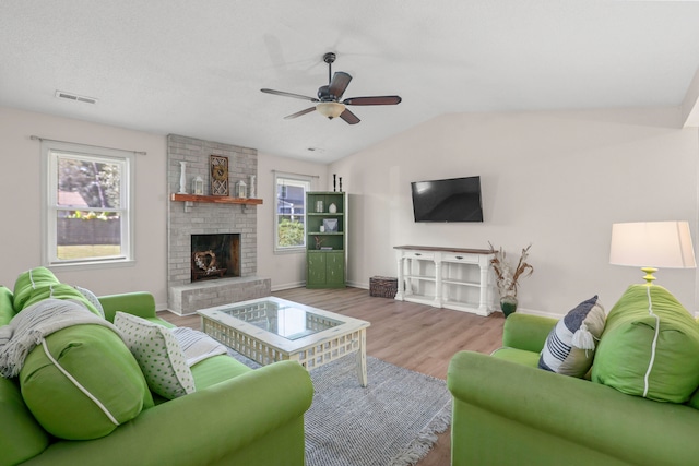 living room featuring light hardwood / wood-style flooring, lofted ceiling, a fireplace, and ceiling fan