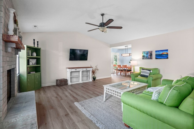 living room featuring lofted ceiling, a fireplace, wood-type flooring, and ceiling fan