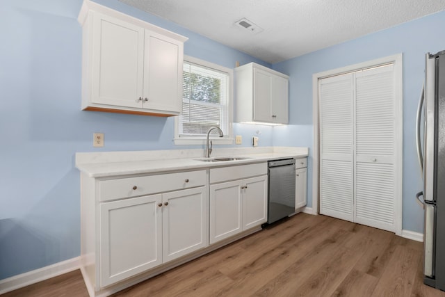 kitchen featuring appliances with stainless steel finishes, sink, white cabinets, and light wood-type flooring