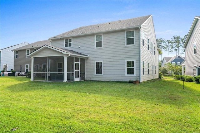 rear view of house featuring a lawn and a sunroom