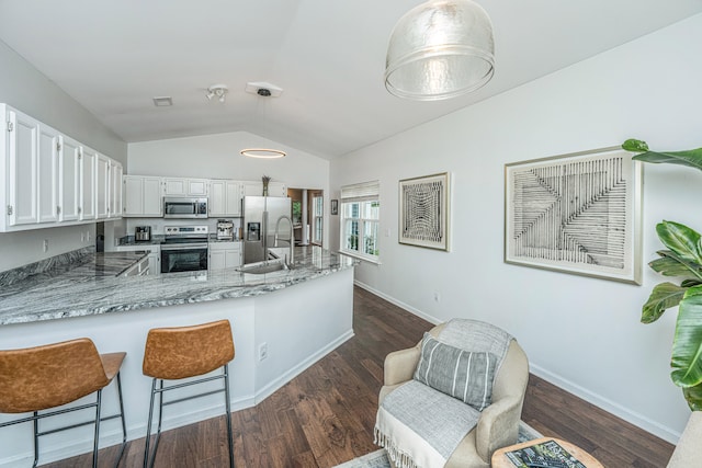 kitchen with white cabinetry, stainless steel appliances, dark hardwood / wood-style flooring, kitchen peninsula, and vaulted ceiling