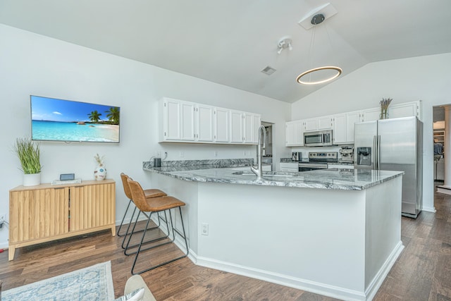 kitchen with white cabinets, vaulted ceiling, appliances with stainless steel finishes, decorative light fixtures, and kitchen peninsula