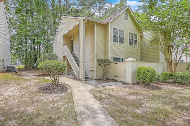 view of front of home with central AC unit, fence, and stairway