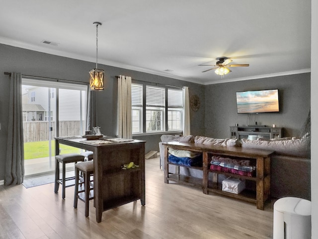 dining space with ornamental molding, light wood-type flooring, and ceiling fan