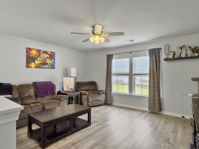 living area featuring light wood finished floors, a ceiling fan, and baseboards