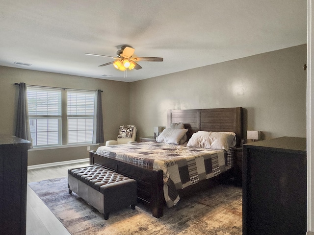 bedroom with a ceiling fan, wood finished floors, and baseboards