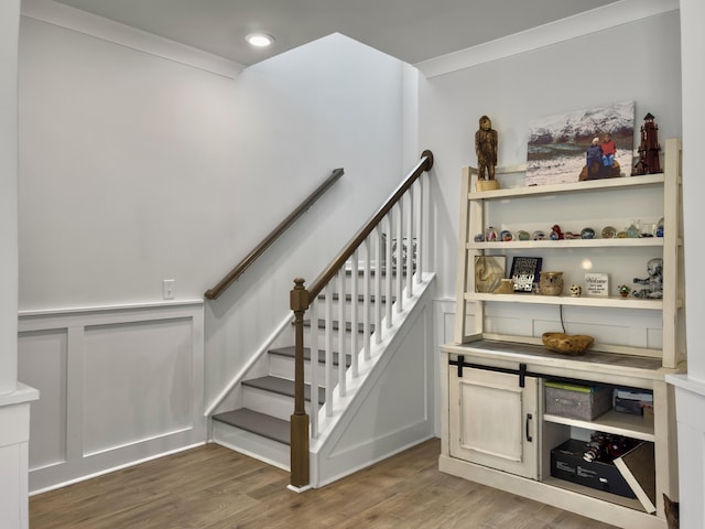 stairway with wood finished floors, recessed lighting, and ornamental molding