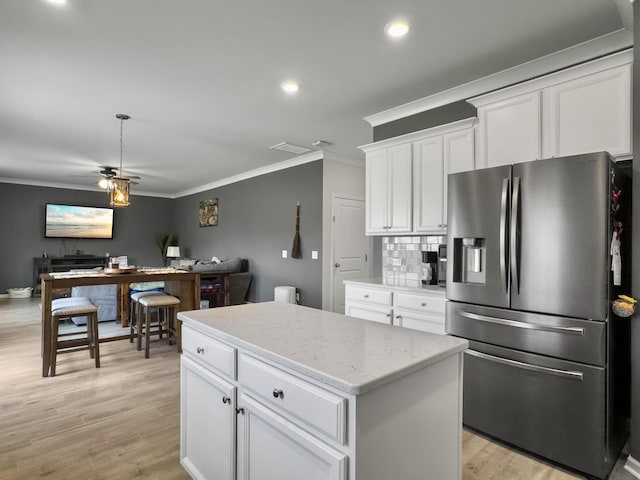 kitchen featuring stainless steel fridge, ornamental molding, a desk, a center island, and white cabinets