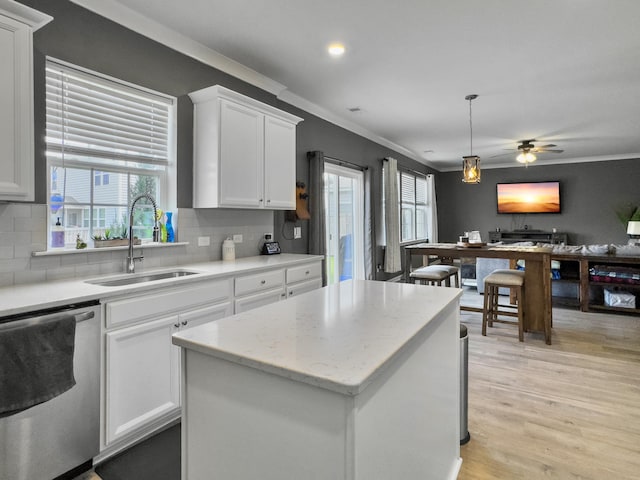 kitchen with a sink, dishwasher, ornamental molding, white cabinets, and backsplash