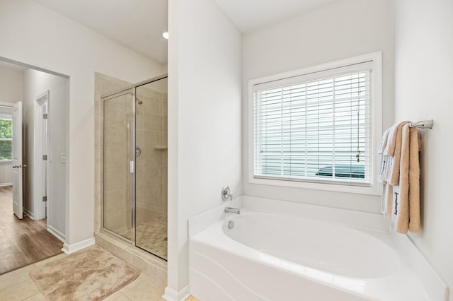 bathroom featuring a healthy amount of sunlight, wood-type flooring, and shower with separate bathtub