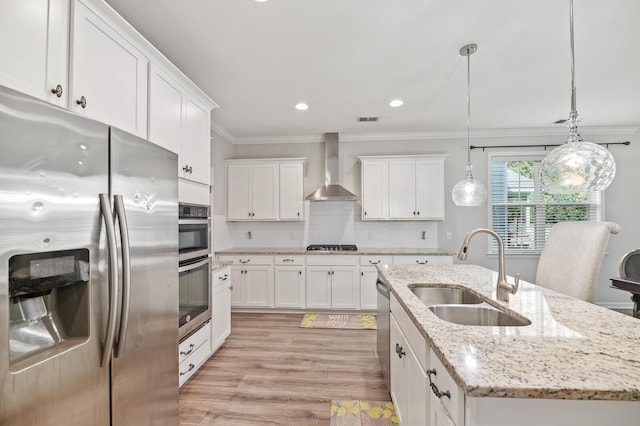 kitchen with a kitchen island with sink, white cabinets, wall chimney range hood, sink, and stainless steel appliances