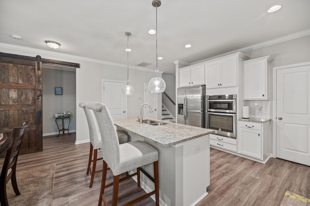 kitchen with a barn door, sink, white cabinets, and appliances with stainless steel finishes