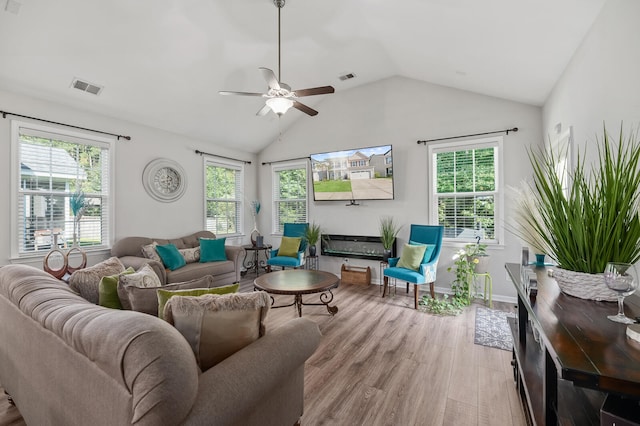 living room with ceiling fan, plenty of natural light, vaulted ceiling, and light hardwood / wood-style flooring