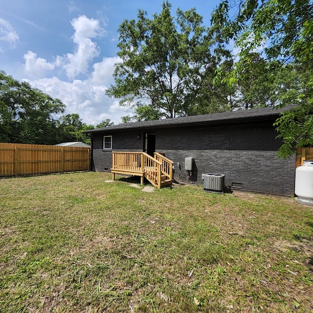 back of property with brick siding, fence, a wooden deck, and a lawn