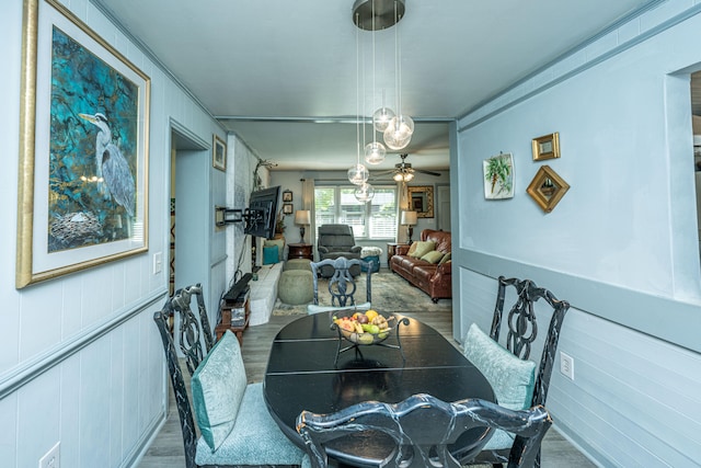 dining room featuring hardwood / wood-style floors, ceiling fan, and wooden walls