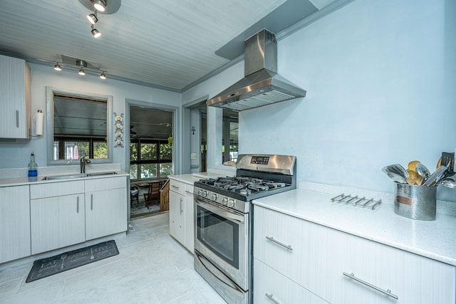 kitchen with rail lighting, wall chimney exhaust hood, stainless steel gas range, sink, and light tile patterned floors