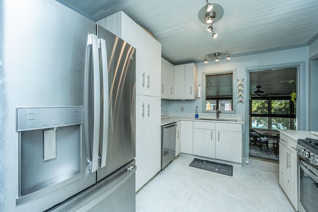 kitchen featuring rail lighting, stainless steel appliances, sink, white cabinetry, and light tile patterned flooring