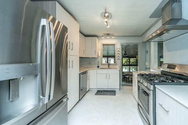 kitchen featuring wall chimney exhaust hood, light tile patterned flooring, sink, and appliances with stainless steel finishes