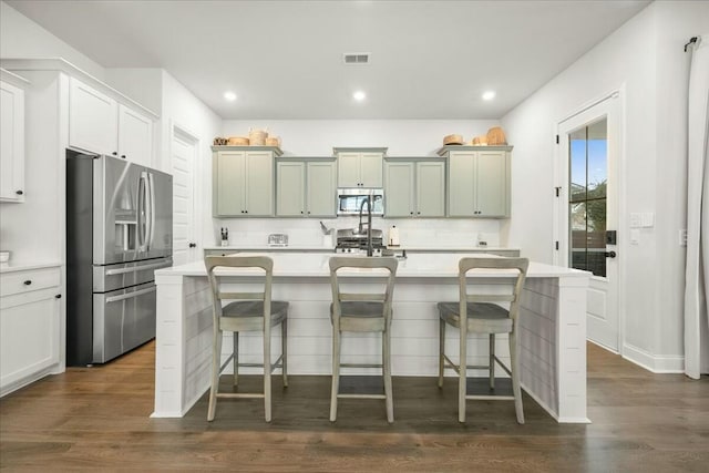 kitchen with a kitchen bar, tasteful backsplash, stainless steel appliances, and a kitchen island with sink