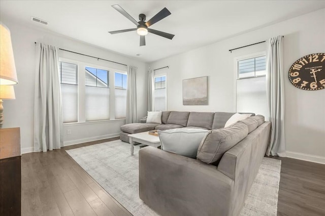 living room with dark wood-type flooring, plenty of natural light, and ceiling fan