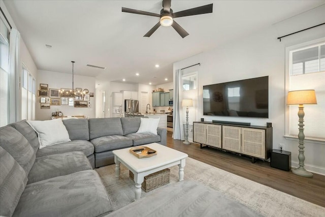 living room featuring wood-type flooring, sink, and ceiling fan with notable chandelier