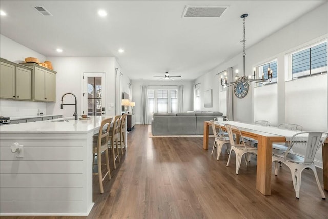 kitchen with decorative light fixtures, dark hardwood / wood-style floors, sink, an island with sink, and ceiling fan with notable chandelier