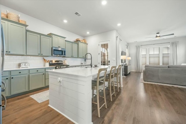 kitchen featuring ceiling fan, sink, a kitchen island with sink, dark wood-type flooring, and stainless steel appliances