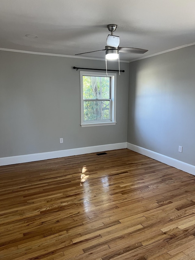 empty room with ceiling fan, ornamental molding, wood finished floors, and visible vents