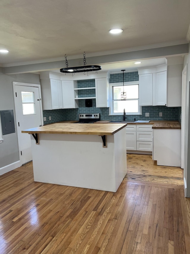 kitchen with a breakfast bar area, a kitchen island, wood counters, and white cabinetry