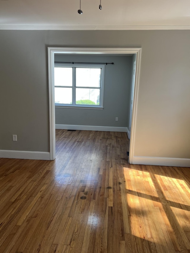 empty room featuring baseboards, dark wood finished floors, and crown molding