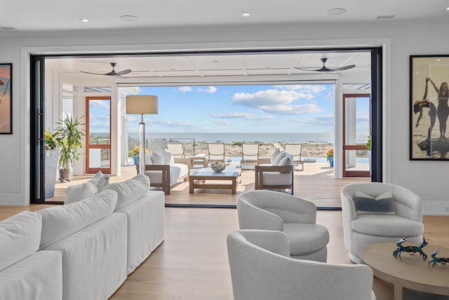 living room with ceiling fan, a water view, and light wood-type flooring