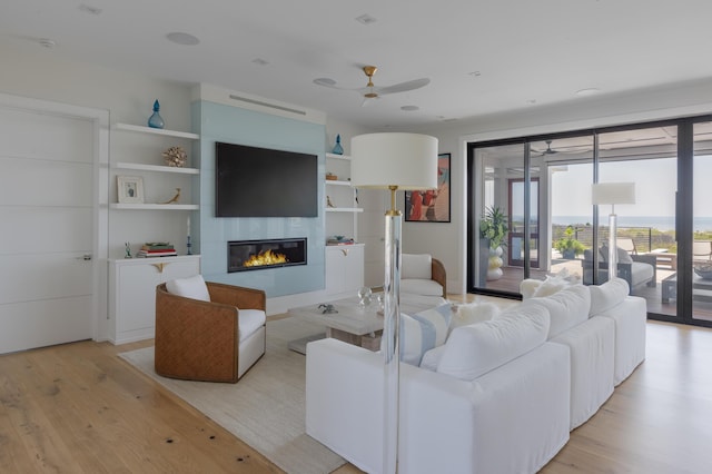 living room featuring ceiling fan, a fireplace, and light hardwood / wood-style floors