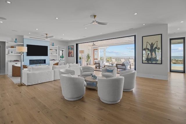 living room with light wood-type flooring, ceiling fan, and a healthy amount of sunlight