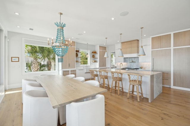 dining space featuring light wood-type flooring, sink, and a chandelier