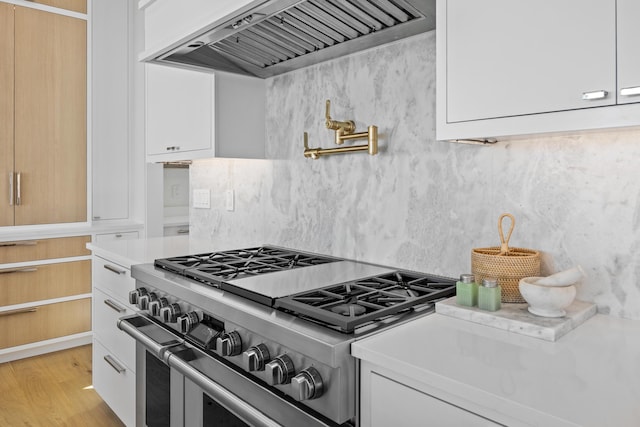 kitchen with white cabinetry, high end stove, custom range hood, and light wood-type flooring