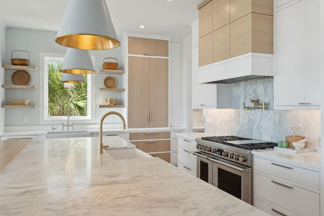 kitchen with white cabinets, light stone countertops, and high end stainless steel range oven