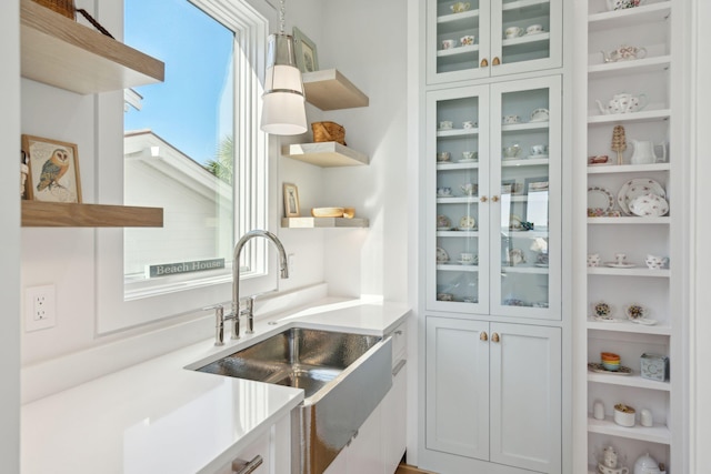 kitchen with sink, white cabinets, and hanging light fixtures