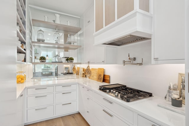 kitchen featuring light hardwood / wood-style floors, white cabinetry, stainless steel gas cooktop, and custom exhaust hood