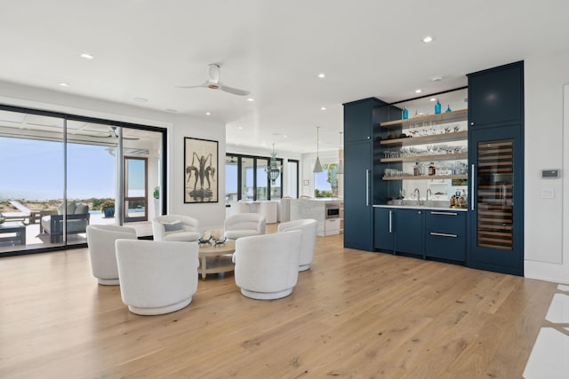 living room featuring wine cooler, light hardwood / wood-style flooring, ceiling fan, and indoor wet bar