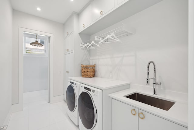 clothes washing area featuring cabinets, light tile patterned floors, sink, and washing machine and clothes dryer