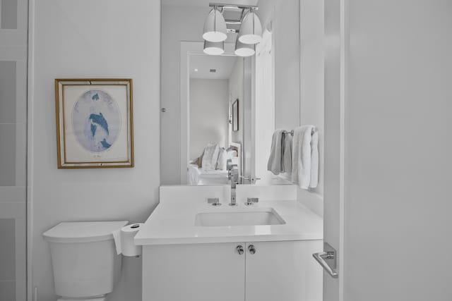 bathroom featuring vanity, a notable chandelier, and toilet