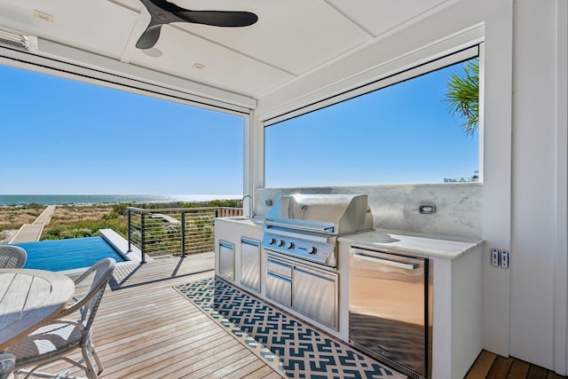 view of patio / terrace featuring ceiling fan, exterior kitchen, grilling area, a balcony, and a water view