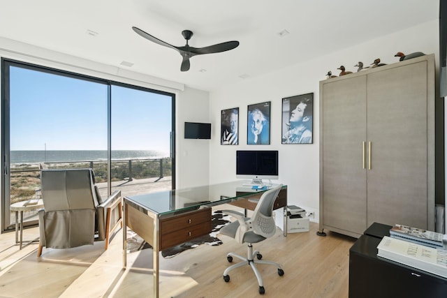 home office with light wood-type flooring and ceiling fan