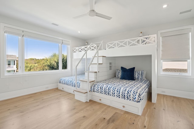 bedroom with hardwood / wood-style floors, ceiling fan, and multiple windows