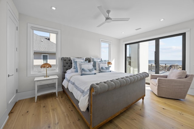 bedroom featuring ceiling fan, a water view, light wood-type flooring, and multiple windows