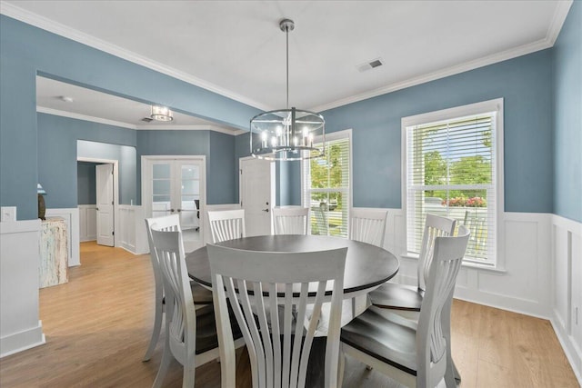 dining space featuring visible vents, light wood-style floors, french doors, wainscoting, and an inviting chandelier