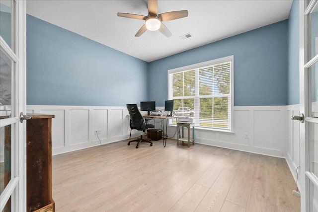 office area with visible vents, a decorative wall, wainscoting, ceiling fan, and wood finished floors