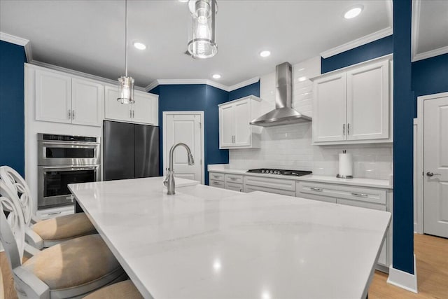 kitchen with built in fridge, stainless steel double oven, a sink, wall chimney range hood, and gas cooktop