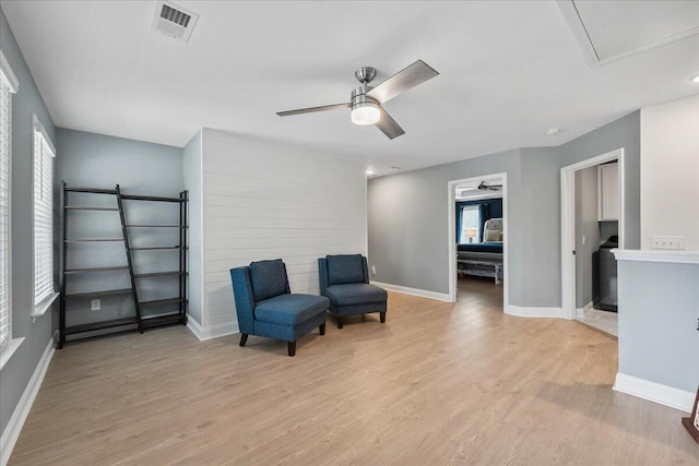 living area with light wood finished floors, baseboards, visible vents, and ceiling fan